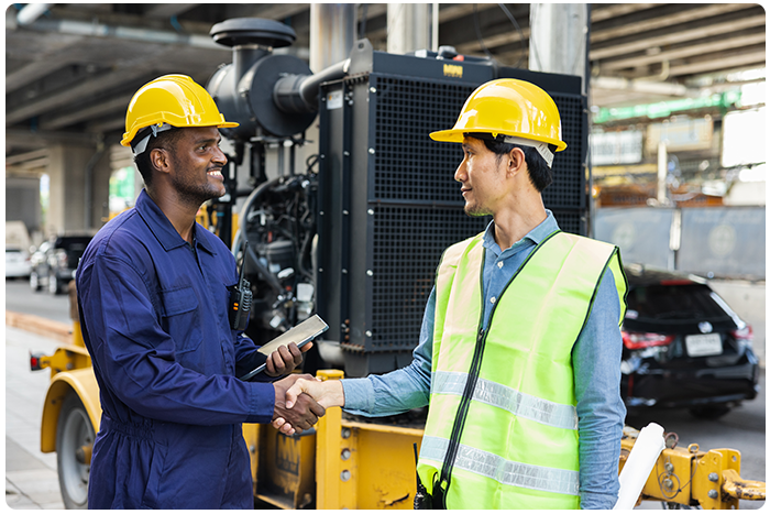 EHS specialist and frontline worker shake hands in front of construction equipment