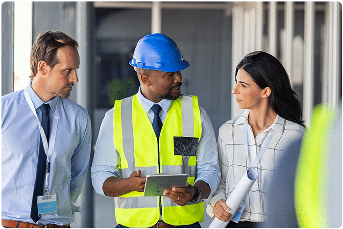 Three EHS specialists discuss safety inspections while one holds a mobile device